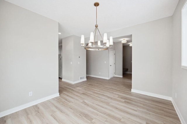 unfurnished dining area with visible vents, a notable chandelier, light wood-style flooring, and baseboards