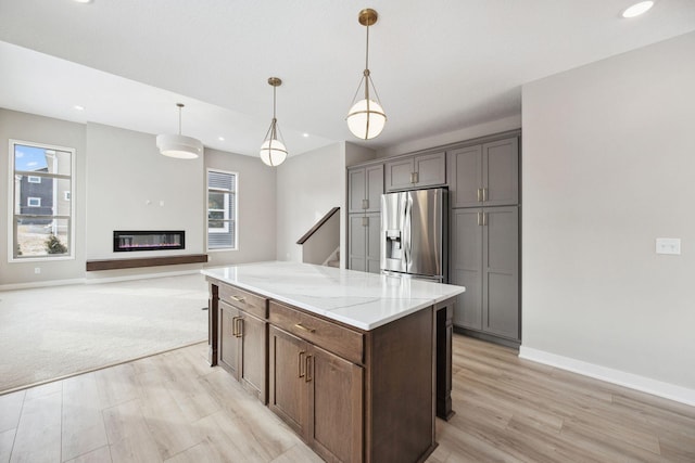 kitchen featuring a kitchen island, baseboards, light wood-type flooring, stainless steel fridge with ice dispenser, and decorative light fixtures