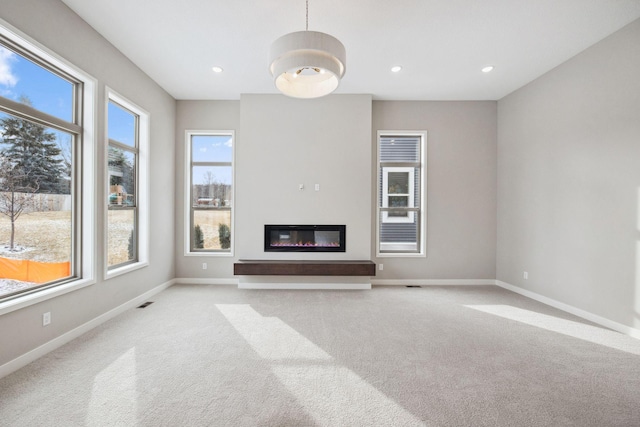 unfurnished living room featuring recessed lighting, carpet, a glass covered fireplace, and baseboards