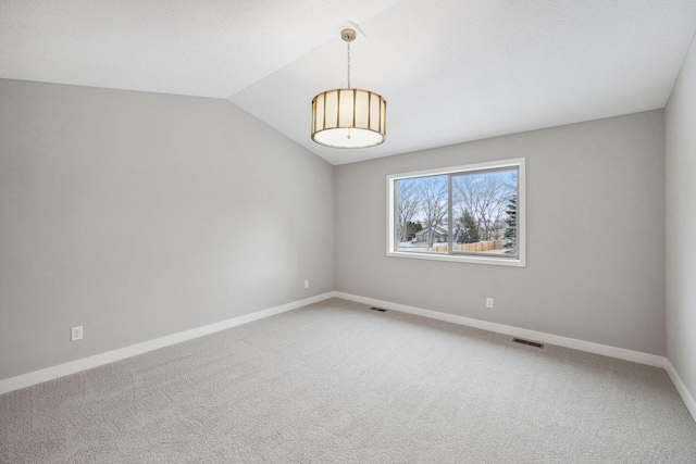 carpeted spare room with lofted ceiling, visible vents, and baseboards