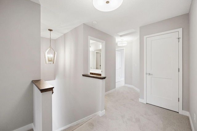 hallway featuring carpet floors, baseboards, and an upstairs landing