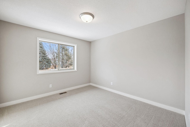 unfurnished room with carpet floors, baseboards, visible vents, and a textured ceiling