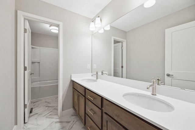 full bath featuring marble finish floor, a sink, a textured ceiling, and double vanity