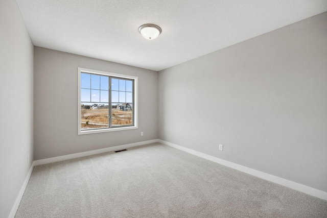 spare room featuring visible vents, carpet flooring, a textured ceiling, and baseboards