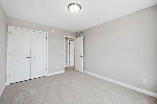 unfurnished bedroom with carpet, a closet, visible vents, and baseboards