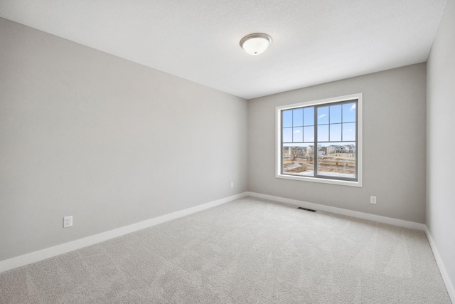 carpeted spare room with visible vents and baseboards