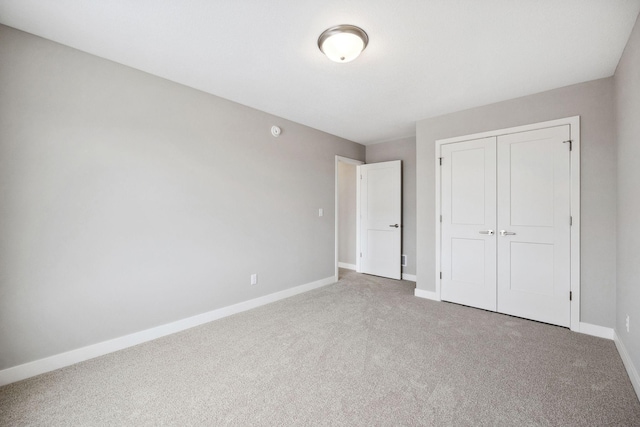 unfurnished bedroom with a closet, carpet flooring, and baseboards