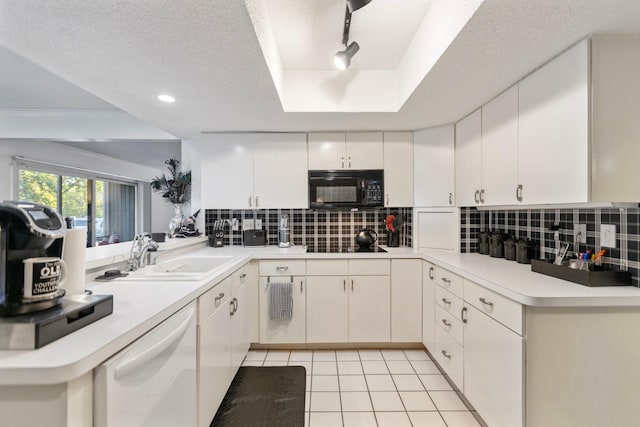 kitchen featuring light tile patterned floors, a textured ceiling, backsplash, black appliances, and a raised ceiling