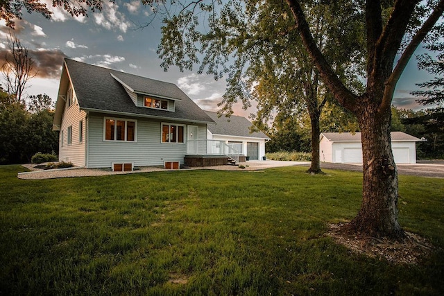 rear view of property featuring a garage, an outbuilding, a yard, and a shingled roof