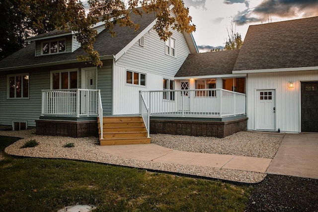 rear view of house with roof with shingles and an attached garage