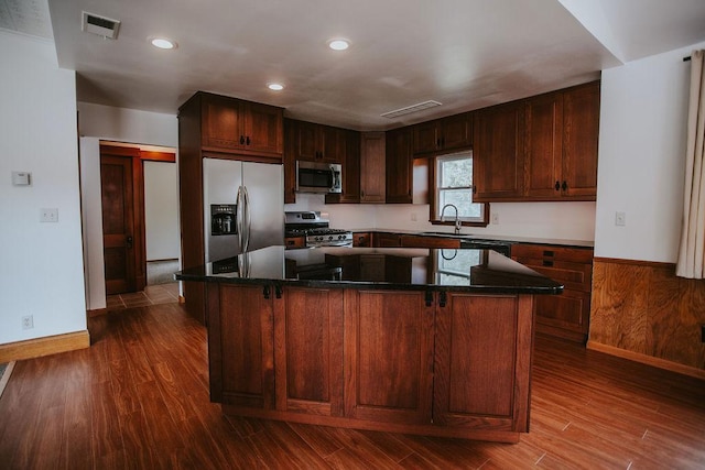 kitchen featuring visible vents, dark wood finished floors, a sink, appliances with stainless steel finishes, and a center island