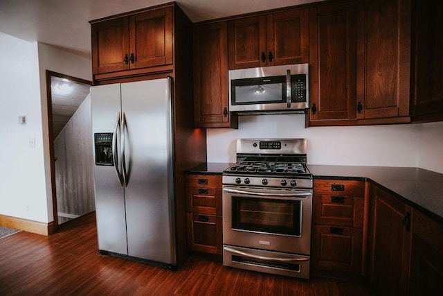 kitchen with dark wood-type flooring, dark countertops, appliances with stainless steel finishes, baseboards, and dark brown cabinets