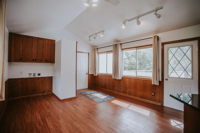 interior space featuring lofted ceiling, wooden walls, and dark wood finished floors