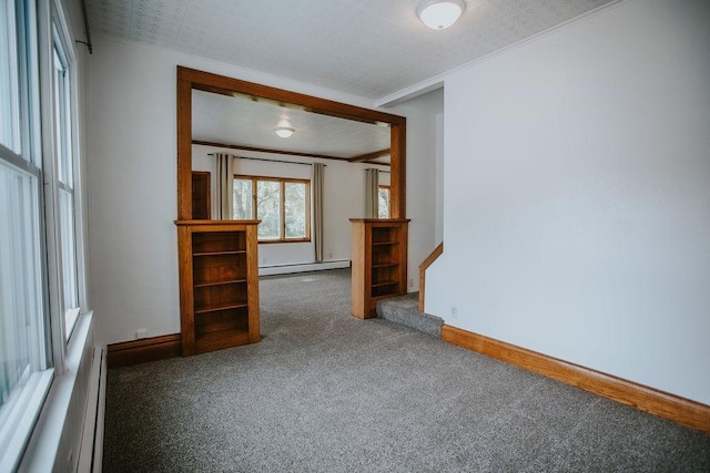 carpeted spare room featuring stairway, baseboards, a baseboard heating unit, crown molding, and baseboard heating