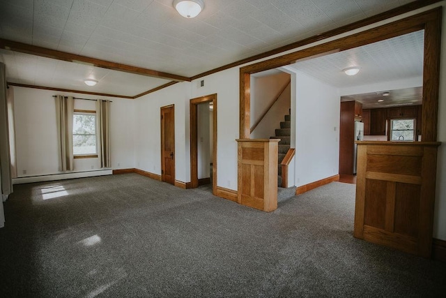 carpeted empty room featuring crown molding, a baseboard heating unit, baseboards, stairs, and beam ceiling