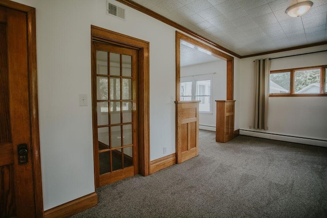 carpeted spare room with ornamental molding, visible vents, a wealth of natural light, and a baseboard radiator