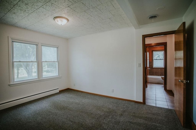 spare room featuring visible vents, a baseboard heating unit, carpet, tile patterned flooring, and baseboards