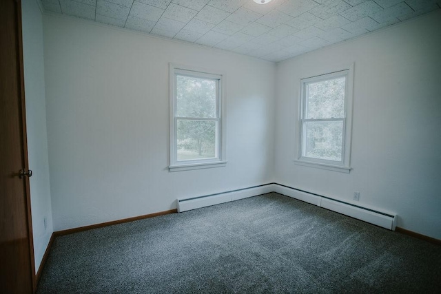 carpeted empty room with a baseboard heating unit, baseboards, and a wealth of natural light