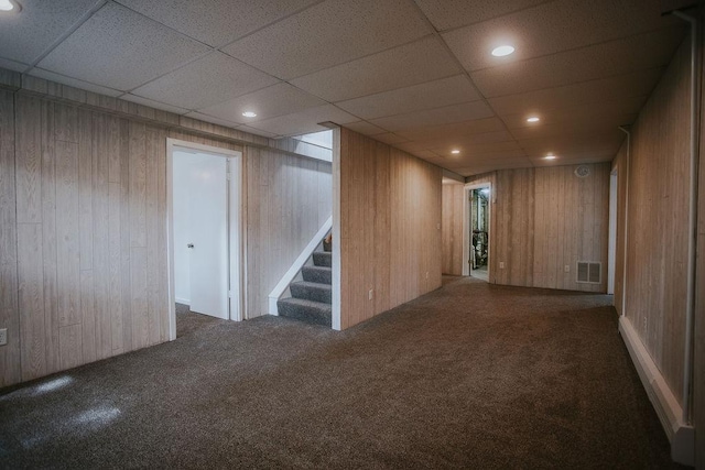 finished below grade area with visible vents, recessed lighting, stairway, wood walls, and carpet flooring