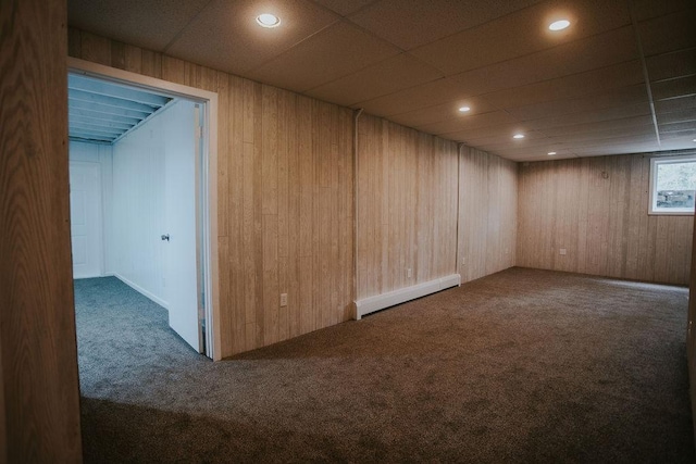 below grade area featuring carpet flooring, wooden walls, and a baseboard radiator