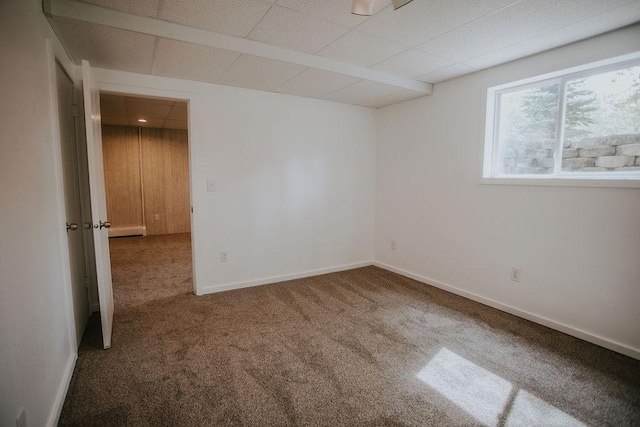 carpeted spare room featuring baseboards and a paneled ceiling