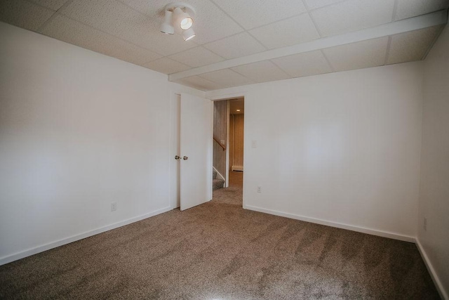 empty room featuring stairway, carpet flooring, a paneled ceiling, and baseboards