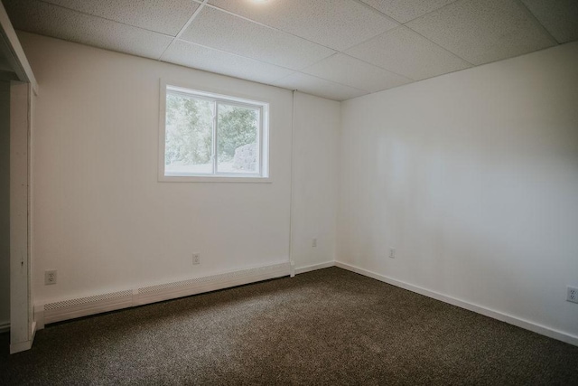 unfurnished room featuring baseboard heating, a drop ceiling, baseboards, and dark colored carpet