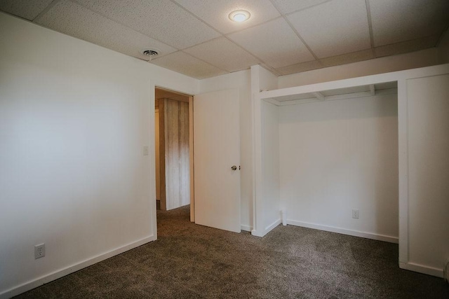 carpeted empty room featuring a paneled ceiling, visible vents, and baseboards