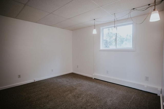 basement featuring baseboards, a paneled ceiling, dark colored carpet, and a baseboard radiator