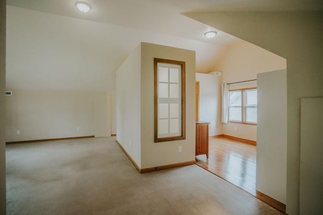 additional living space featuring baseboards, lofted ceiling, and light carpet