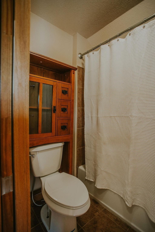 full bathroom featuring tile patterned floors, toilet, shower / bath combo, and a textured ceiling