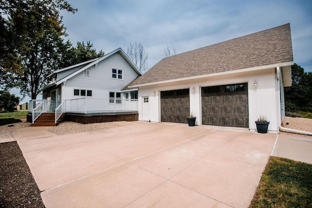 view of front of property featuring an outbuilding, an attached garage, driveway, and a shingled roof