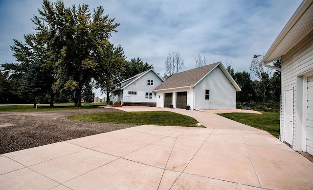 view of property exterior with a yard, an outbuilding, a garage, and driveway