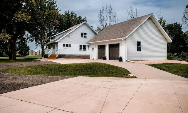 back of house featuring a yard, an attached garage, roof with shingles, and driveway