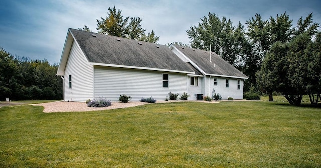 back of house featuring a yard, roof with shingles, and central AC unit