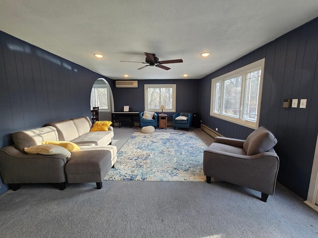 living area with arched walkways, carpet floors, baseboard heating, and a wall mounted air conditioner