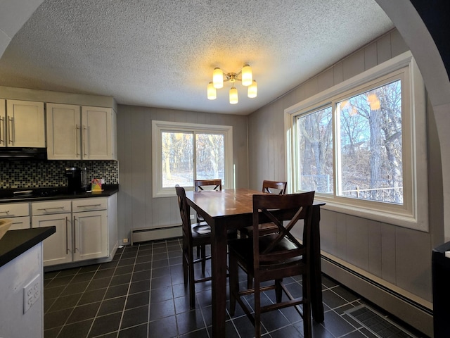 dining room with dark tile patterned floors, a baseboard radiator, arched walkways, and a textured ceiling