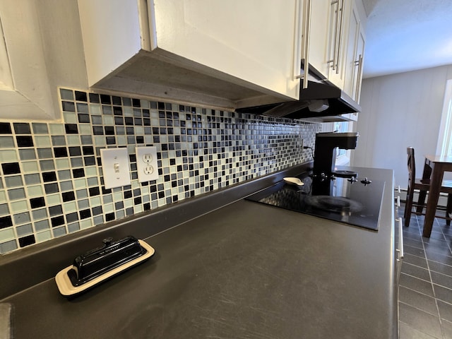 kitchen with dark countertops, black electric cooktop, white cabinets, and decorative backsplash