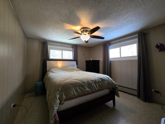 bedroom with a ceiling fan, light colored carpet, baseboard heating, a textured ceiling, and wood walls