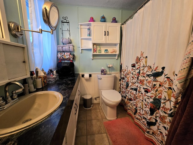 bathroom featuring a textured ceiling, tile patterned flooring, toilet, a shower with shower curtain, and vanity