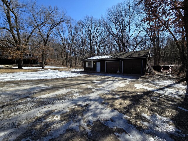 snow covered garage featuring driveway