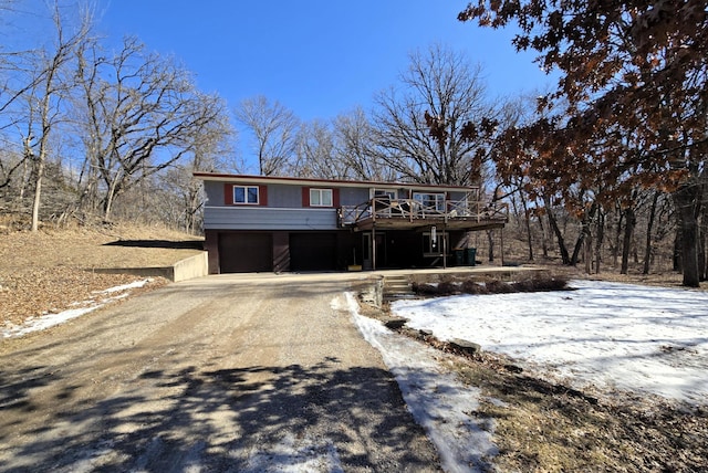 view of front of property with an attached garage, dirt driveway, and a deck