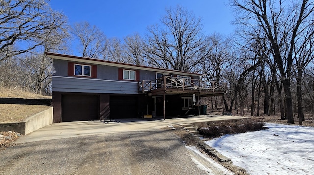 view of front of property featuring a garage, asphalt driveway, and a wooden deck