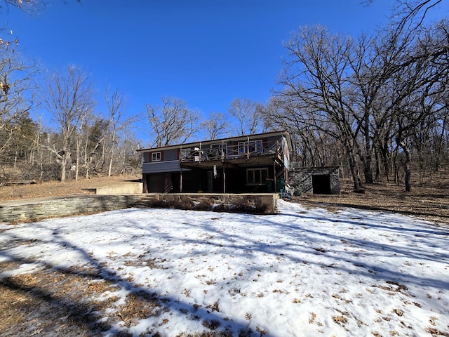 snow covered back of property featuring a deck