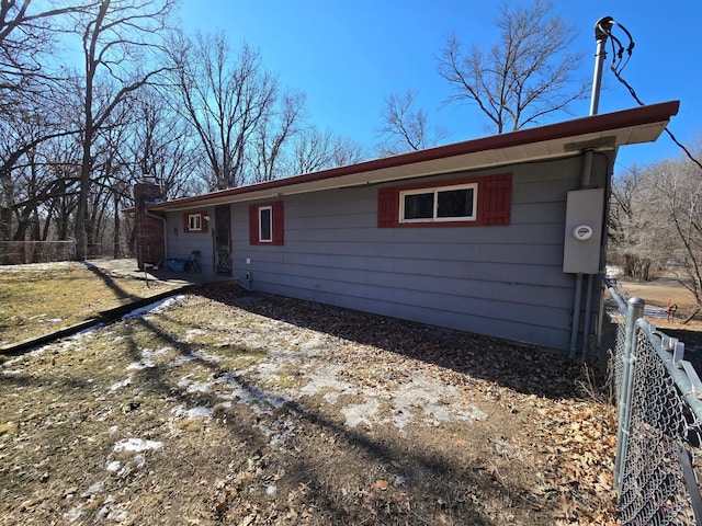 single story home featuring a chimney and fence