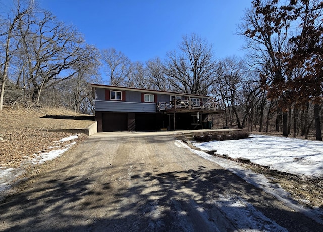 view of front of house with asphalt driveway, a deck, and a garage