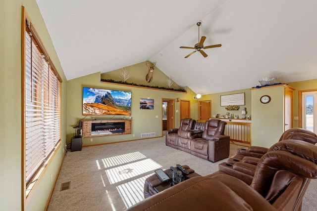 living area with carpet, a glass covered fireplace, visible vents, and a ceiling fan