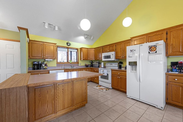 kitchen with white appliances, light tile patterned floors, a kitchen island, brown cabinets, and a sink