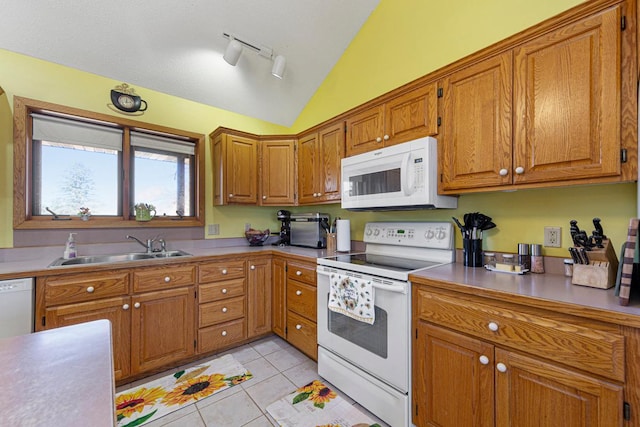 kitchen featuring vaulted ceiling, white appliances, a sink, and brown cabinets