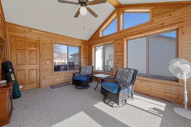 living area with high vaulted ceiling, wood walls, carpet flooring, and a ceiling fan